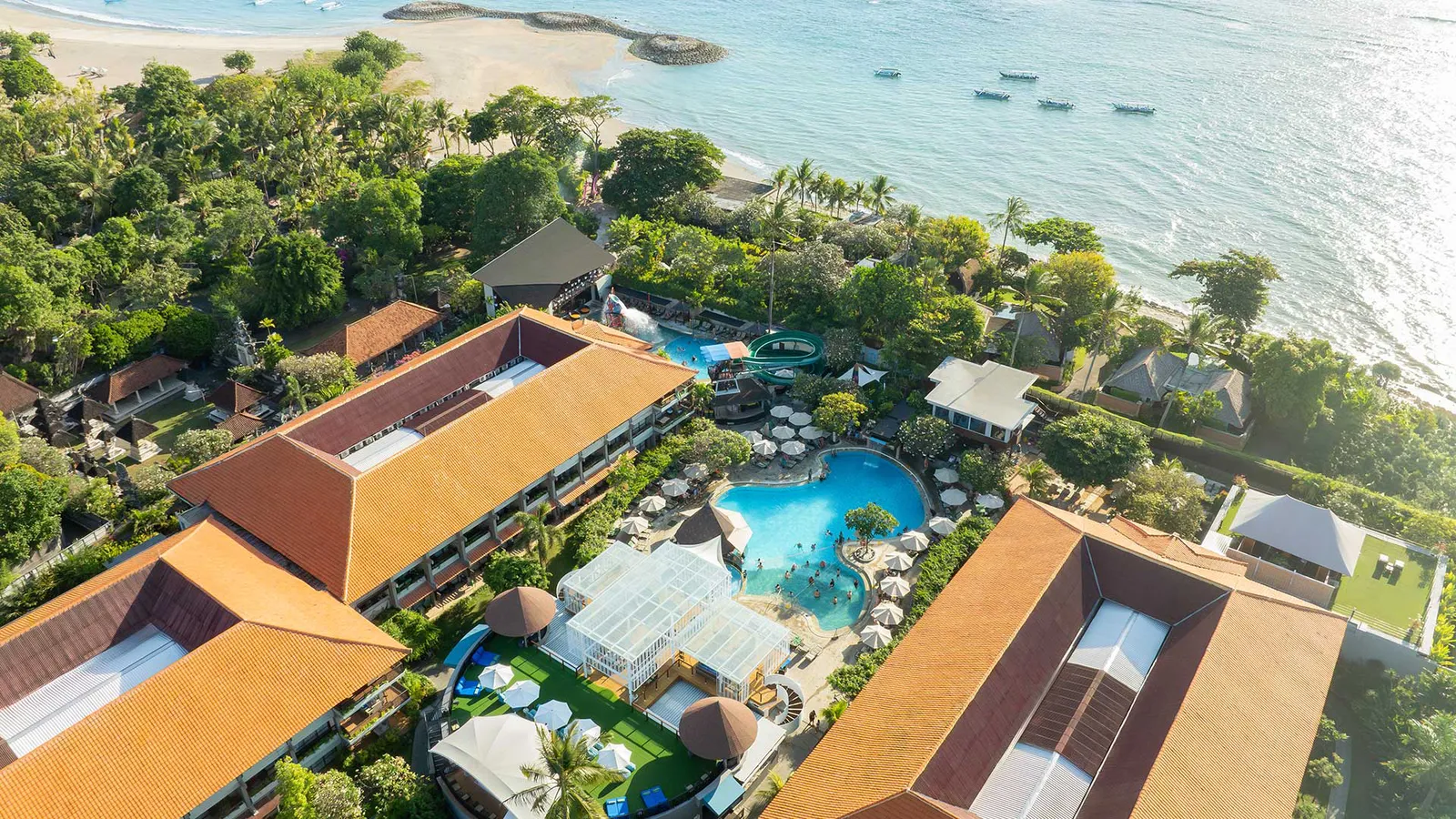 Aerial view of Bali Dynasty Resort in Tuban, showing its four pools, tropical gardens and room blocks running down toward the beach