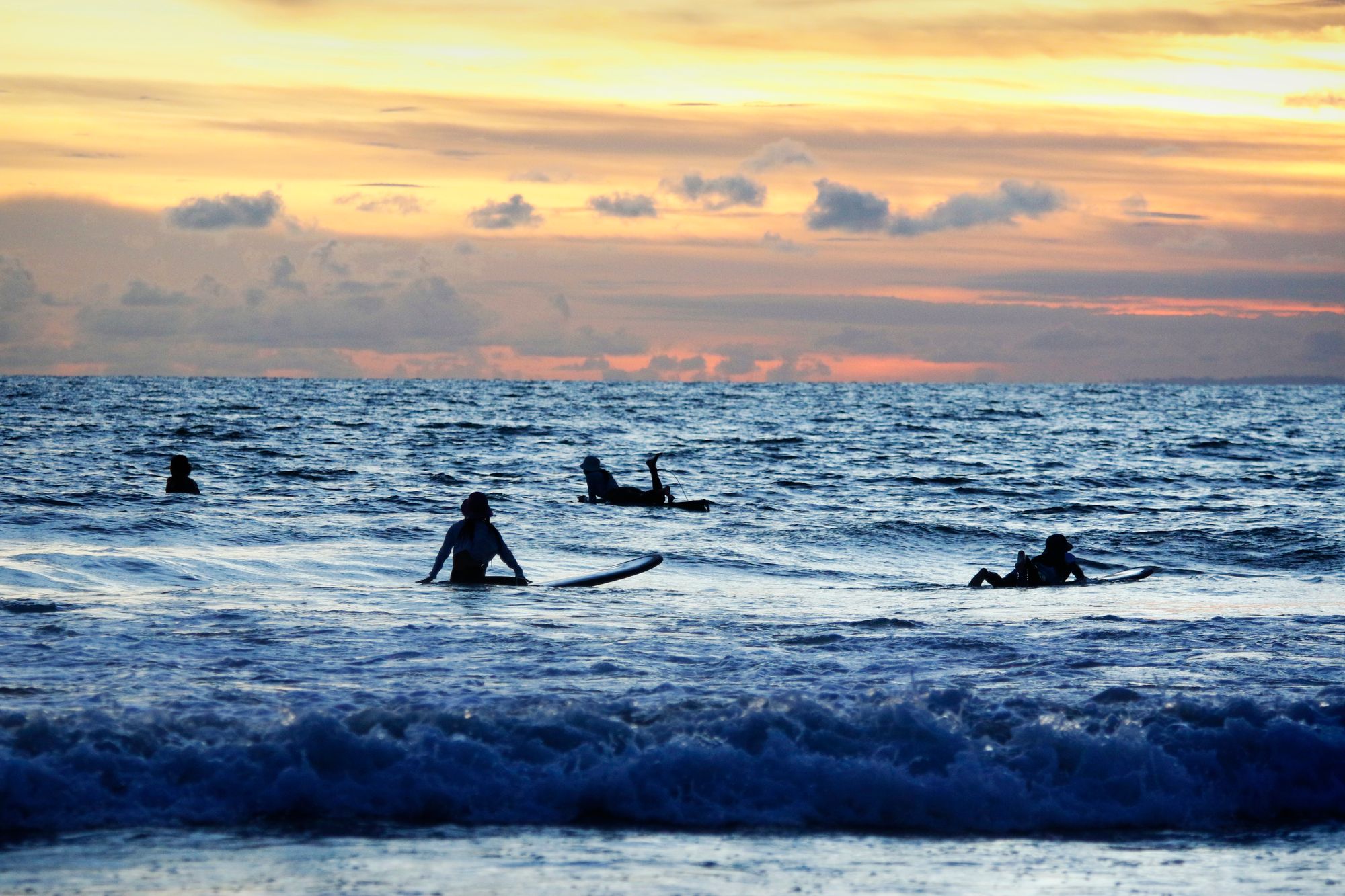 Kuta Beach at golden hour, with calm waves and warm light stretching along the shoreline